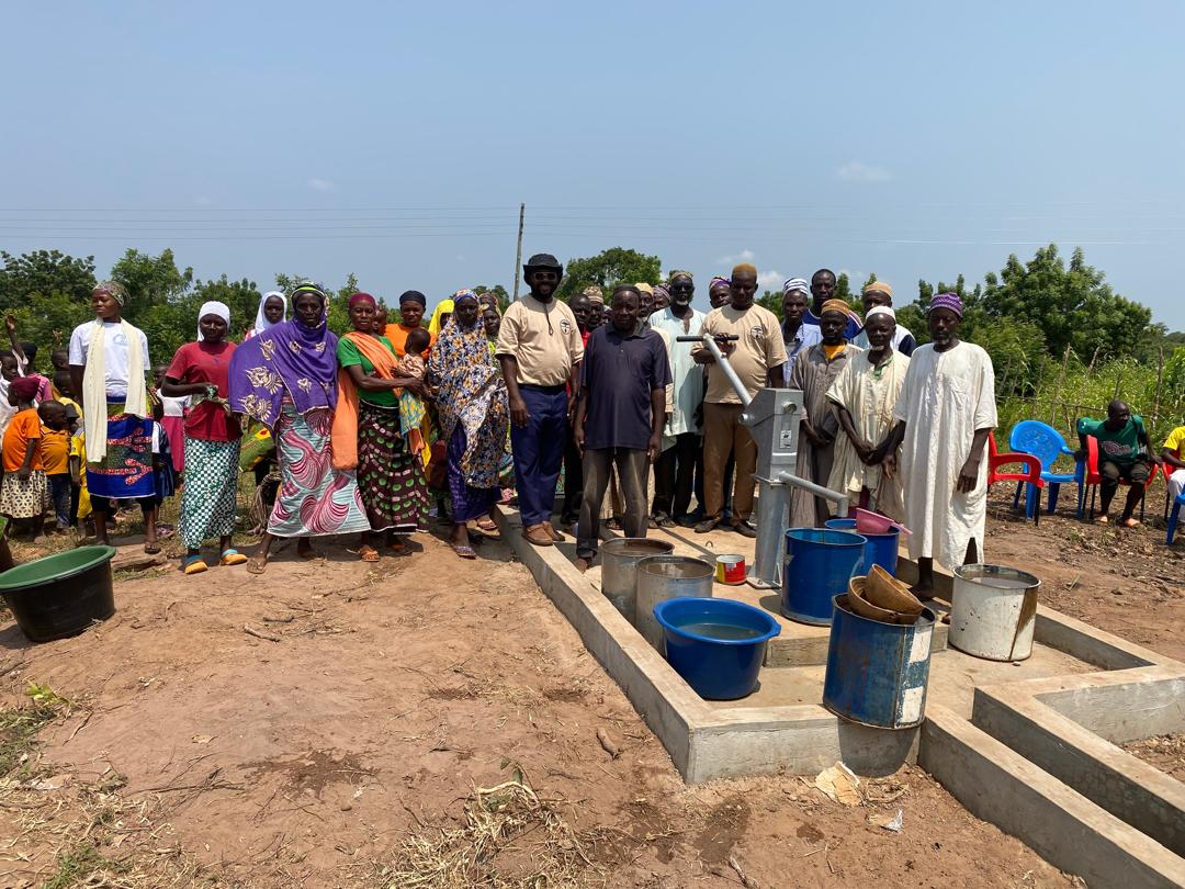 A gathering of children and community members in a village in northern Ghana